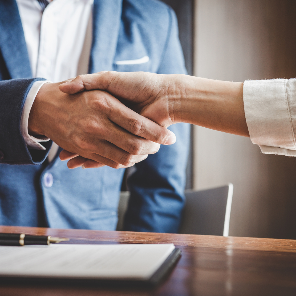 Zwei Personen in Business-Kleidung geben sich die Hand, symbolisierend Vertrauen und IT-Sicherheit durch ein IT Systemhaus.