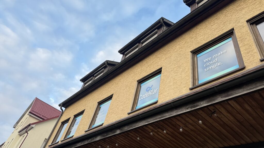 Die Fassade des CodeKlar-Gebäudes zeigt Fenster mit dem Slogan der CodeKlar GmbH: "We make cloud simple."