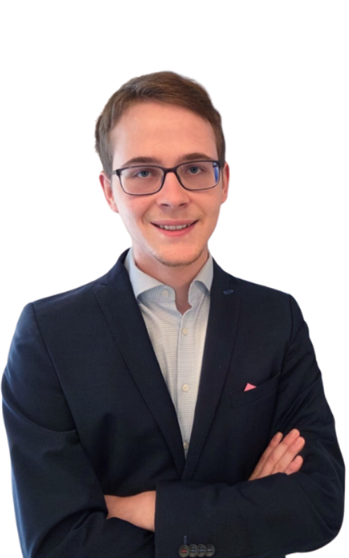 Max von CodeKlar GmbH lächelt freundlich in einem dunklen Anzug mit verschränkten Armen vor einem einfarbigen Hintergrund.